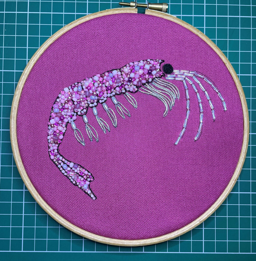 Krill with pink beaded body on pink fabric